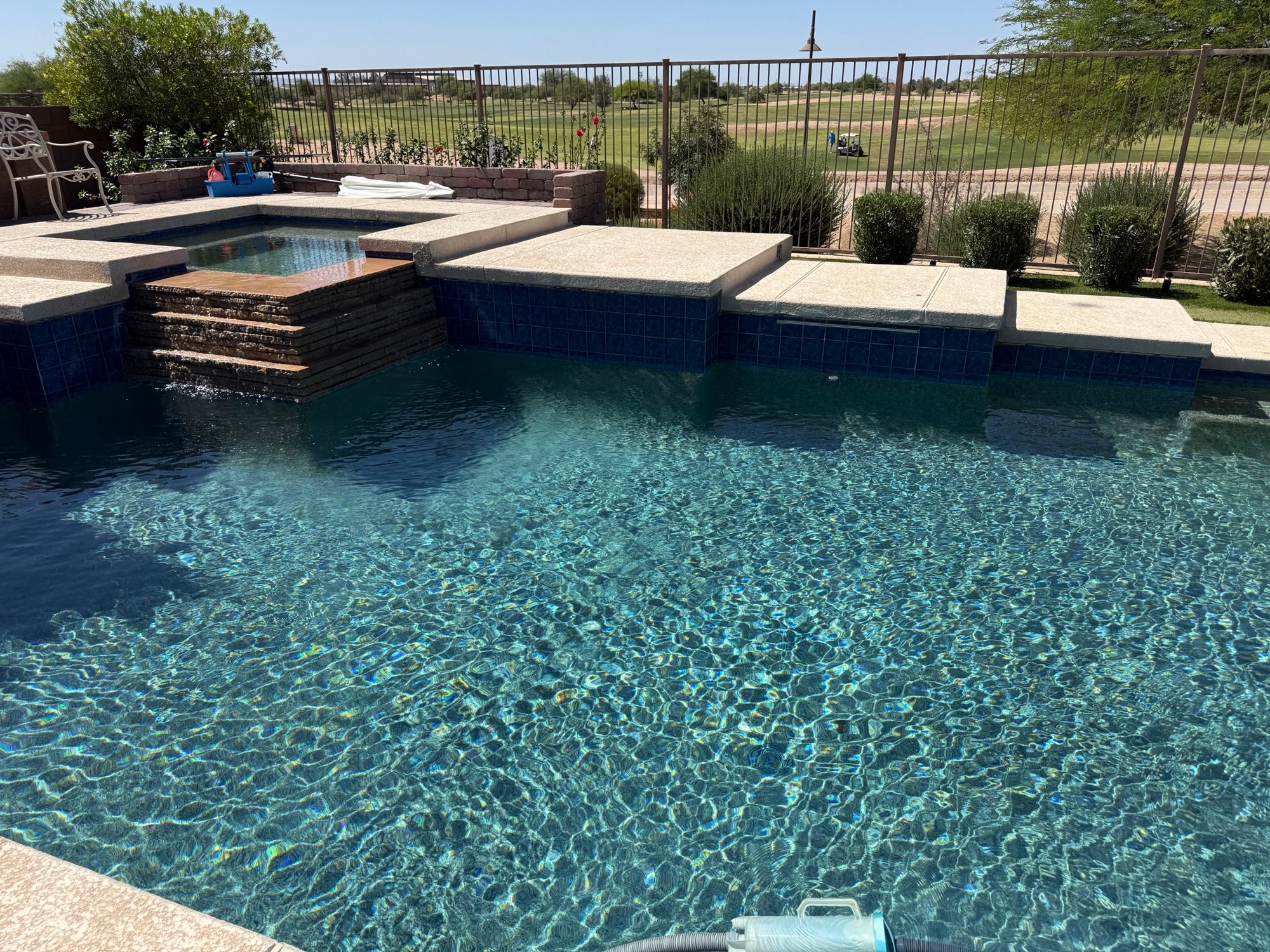 Spa and waterfall steps beside a backyard golf course view