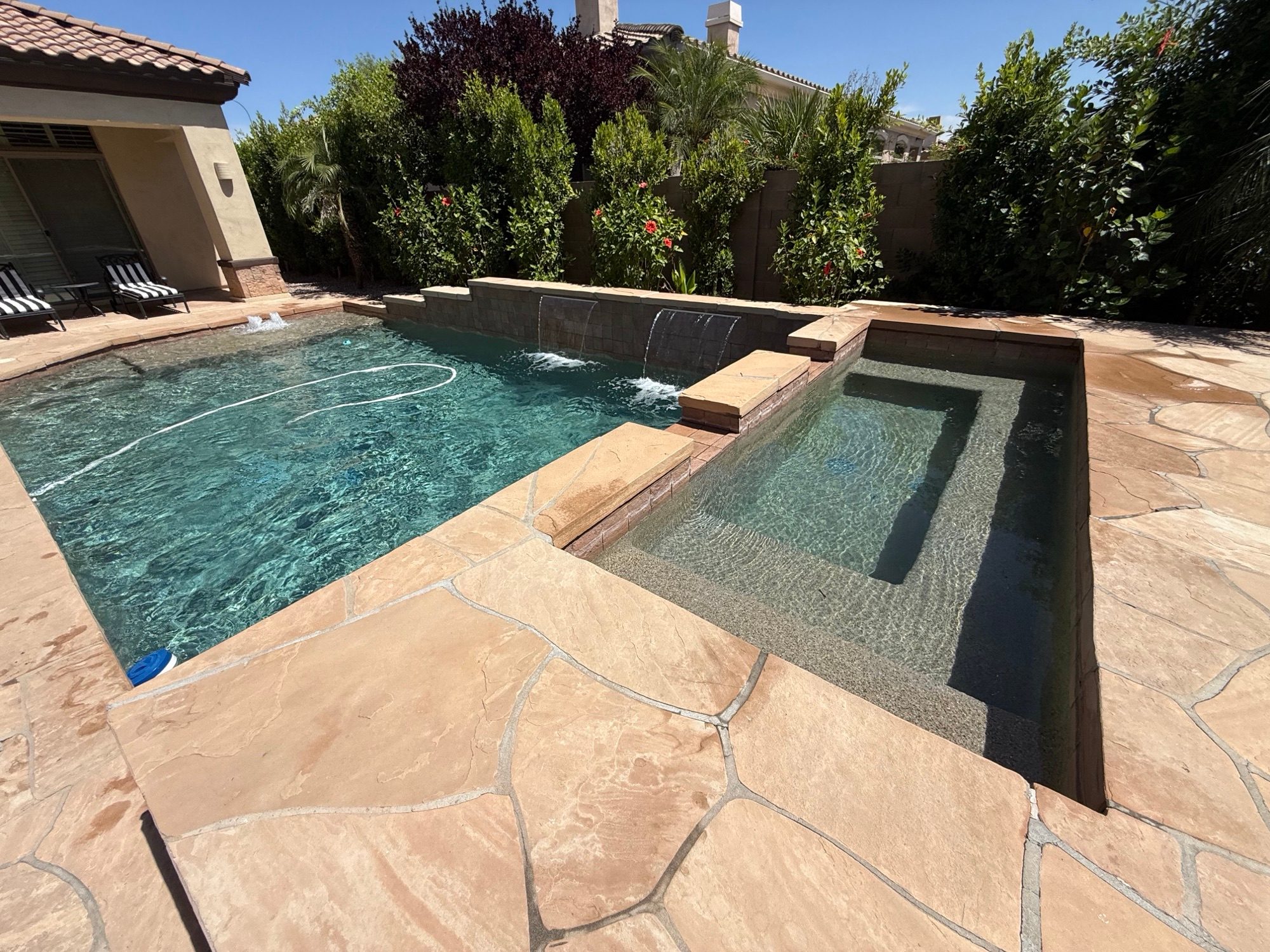 Raised spa with a three-spout waterfall feeding into the pool